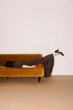 Relaxed Figure Resting On Brown Sofa With Legs Up