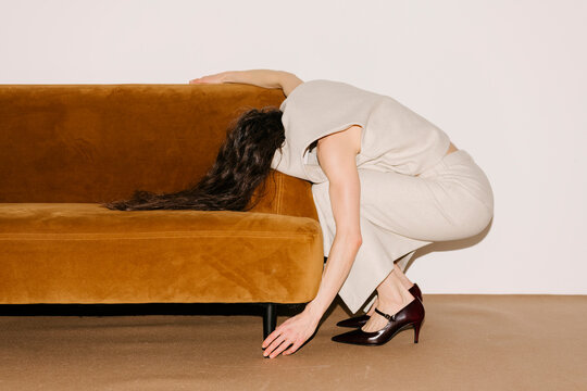 Person Bending Over Couch in Beige Outfit