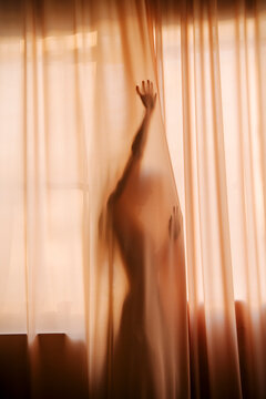Silhouette Behind Curtain in Soft Amber Light