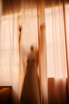 Silhouetted Figure Behind Sheer Curtains