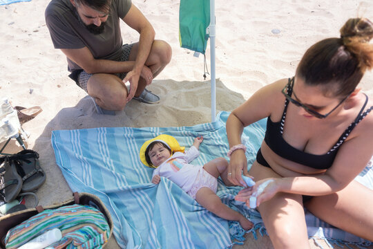 Family on beach with baby applying sunscreen