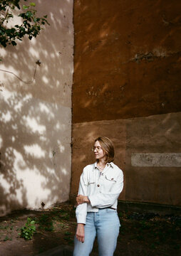 Woman Standing in a Sunny Urban Space Near a Textured Wall