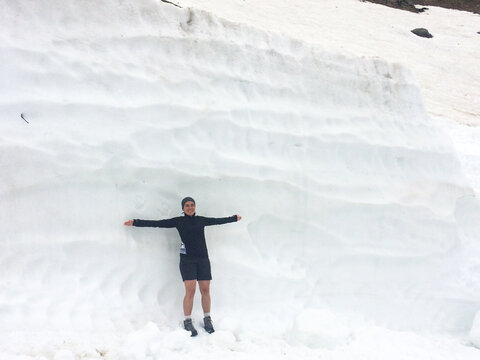 Happy woman with arms wide against snow wall