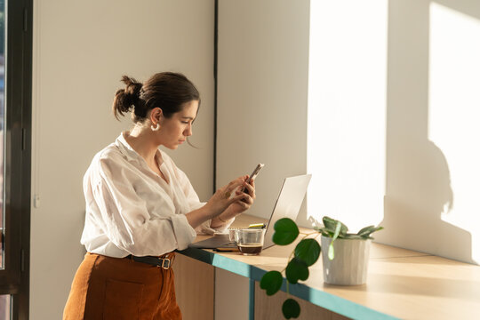 Young Woman Checking Her Phone While Working at a Desk During Morning