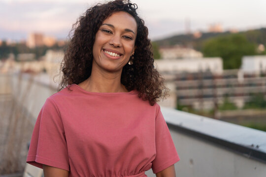 Smiling Woman Posing on Rooftop During Sunset in Urban Setting
