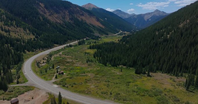 Iconic highway curves by open alpine valley surrounded by San Juan peaks, Million Dollay Highway Colorado USA