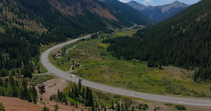 Mountain roadway winding by wide Colorado valley with lush greenery, Million Dollay Highway Colorado USA