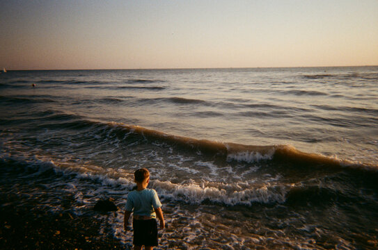 Boy standing in front of seaside during sunset