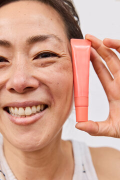 Beautiful asian woman holding lipgloss