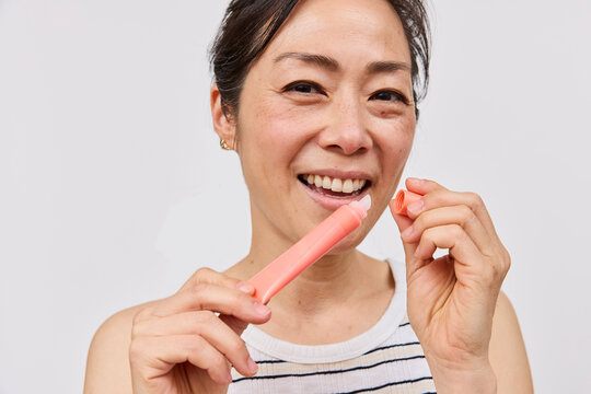 Beautiful asian woman holding lipgloss