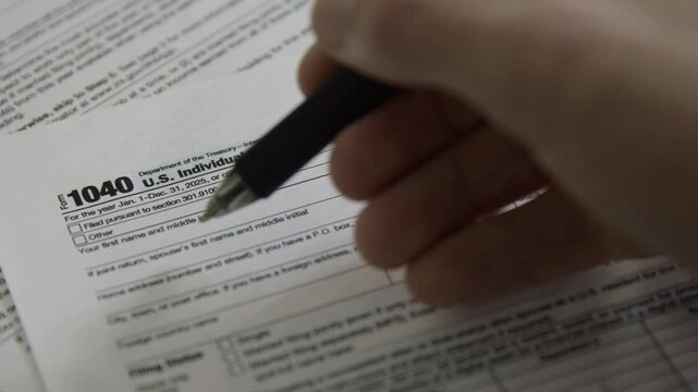 Filling out a 1040 US Individual Income Tax Return. Close up of person filling out tax form