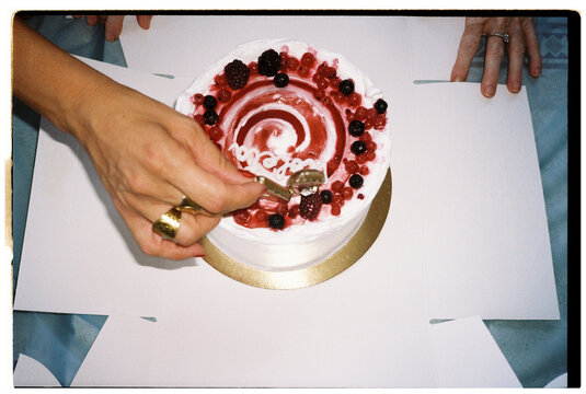Birthday cake with berries and candles being placed