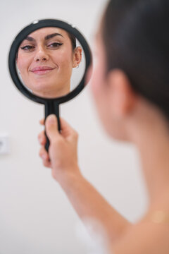 Woman holding hand mirror checking makeup reflection