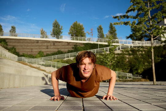 Man performing push-ups outdoors on pavement