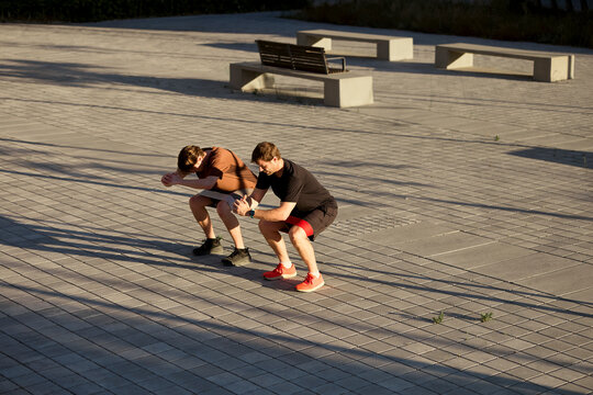 Trainer guiding squat exercise outdoors