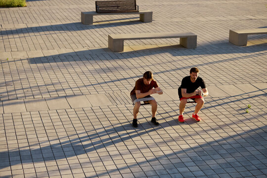 Trainer and client exercising with squats outdoors