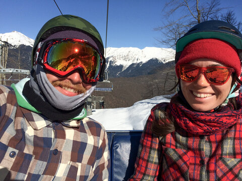 Smiling snowboard couple riding ski lift