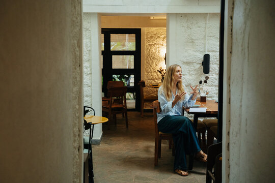 Woman Engaged in Conversation at Cozy Cafe in the Daytime