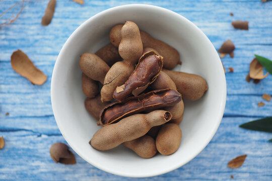 Fresh tamarind fruits in a bowl on a blue wooden table