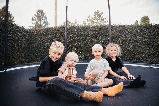blond kids sitting on a trampoline outdoors late summer begin autumn