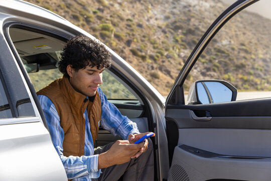 Man outdoors  car road trip texting cell phone 