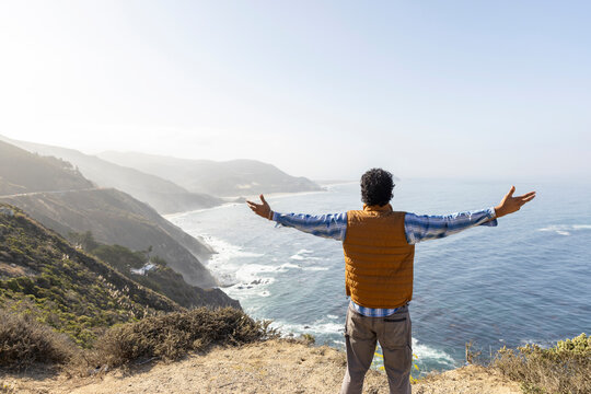 Man Armed raised looking at Big Sur Coast Ocean 
