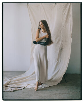Elegant woman in simple dress poses against textured backdrop