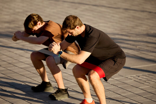 Personal trainer demonstrating squat exercise with client