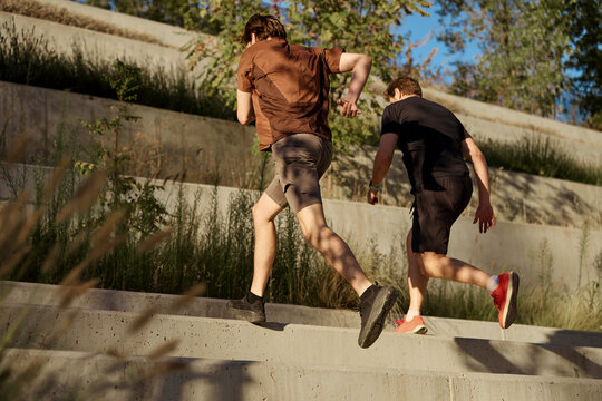 Personal trainer and client sprinting upstairs outdoors