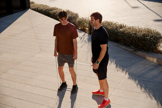 Trainer supervising client with resistance band exercise
