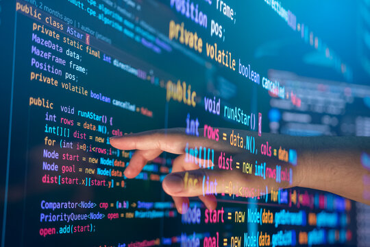 Programmer hand touching code on screen, and develop software, websites, or applications using programming languages JavaScript, and C++ to test and debug to ensure the system functions efficiently.