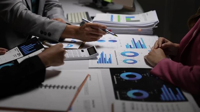Business colleagues analyzing financial reports and graphs during a meeting.