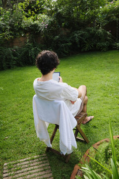 Male reading in a kindle enjoying time alone in the backyard