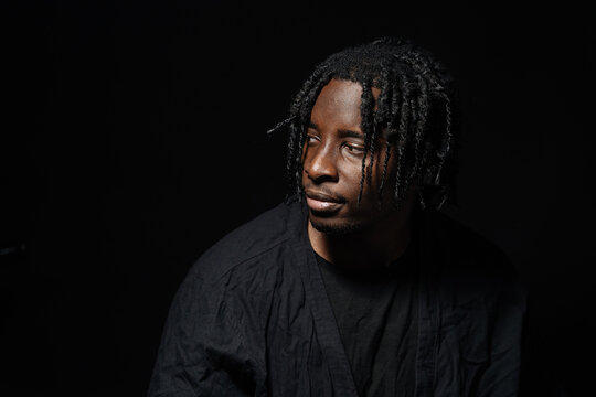 Man in black gazing sideways under dramatic lighting