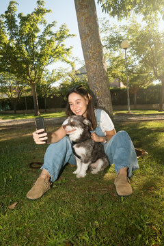 Girl enjoying time outdoors with her dog, taking a selfie in the park