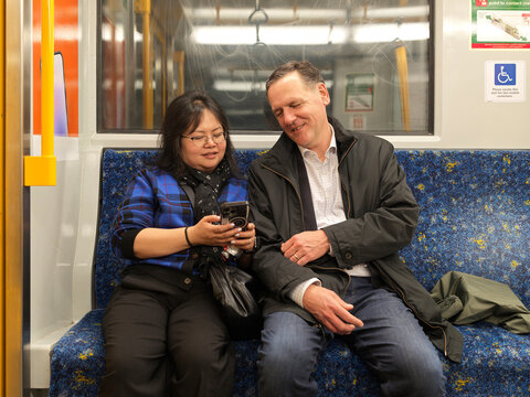 Couple Enjoy a Moment on the Subway While Looking at a Phone