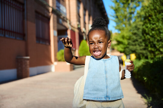 Girl crying outside school building in the morning