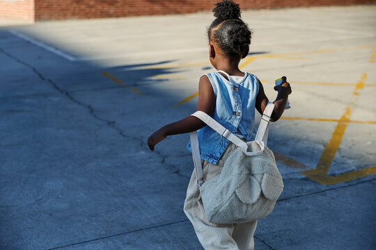 Child walking to school carrying a backpack and drink