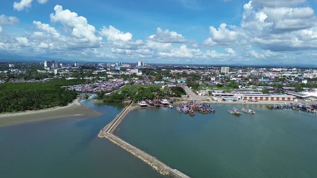 Aerial view of Iloilo City showing tropical coastline and urban skyline under dramatic clouds. Harbor with Anchored Boats, Coastal development and vibrant Philippine city atmosphere from above.