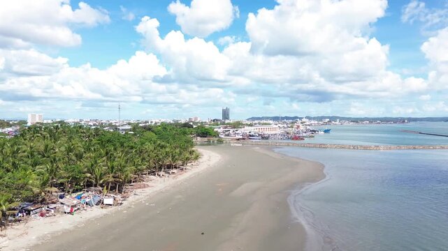 Aerial cityscape of Iloilo City Philippines showing expanding residential districts and tropical coastline under bright clouds. Dynamic urban growth and coastal development on Panay Island.