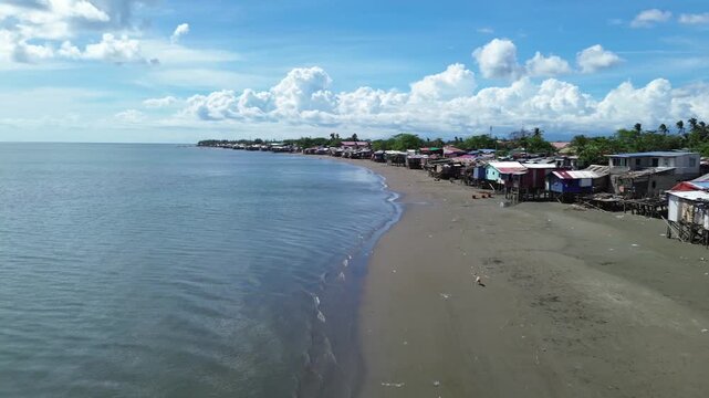 Aerial view of rural coastal neighborhood in Iloilo City Philippines featuring small houses near tropical shoreline. Authentic local community landscape along the urban edge of Panay Island.