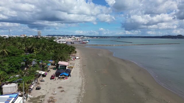 Aerial view of secluded beach in Iloilo City Philippines with scattered small houses along tropical shoreline. Quiet coastal landscape on Panay Island with minimal development and blue waters.