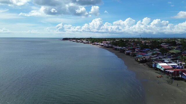 Aerial view of rural coastal neighborhood in Iloilo City Philippines featuring small houses near tropical shoreline. Authentic local community landscape along the urban edge of Panay Island.