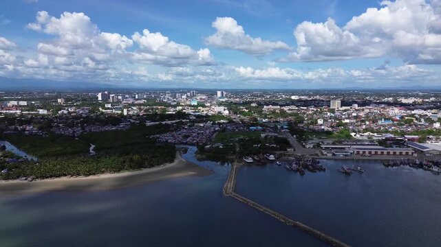 Aerial cityscape of Iloilo City Philippines showing expanding residential districts and tropical coastline under bright clouds. Dynamic urban growth and coastal development on Panay Island.