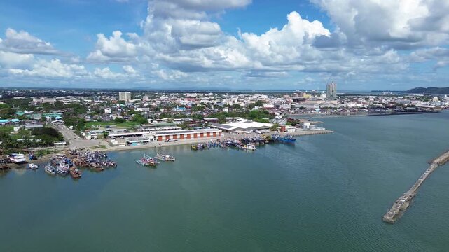 Aerial view of Iloilo City showing tropical coastline and urban skyline under dramatic clouds. Harbor with Anchored Boats, Coastal development and vibrant Philippine city atmosphere from above.