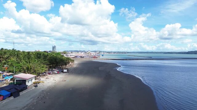 Aerial view of secluded beach in Iloilo City Philippines with scattered small houses along tropical shoreline. Quiet coastal landscape on Panay Island with minimal development and blue waters.