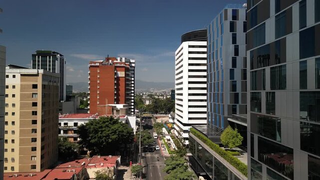 Low aerial flying between buildings in Guatemala City downtown on sunny day