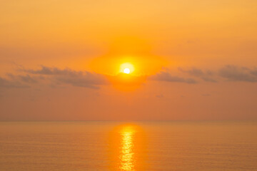 Obraz premium Nature sky breathtaking golden sunset over a calm ocean, with the entire sky and water bathed in brilliant shades of yellow and orange. Streaky clouds enhance the dramatic display of light 