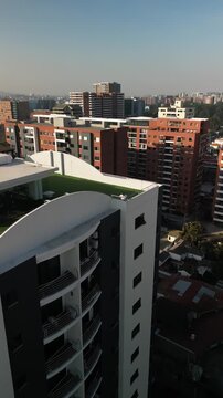 Vertical aerial man of rooftop of skyscraper in downtown Guatemala City zone 14 with smoggy sky