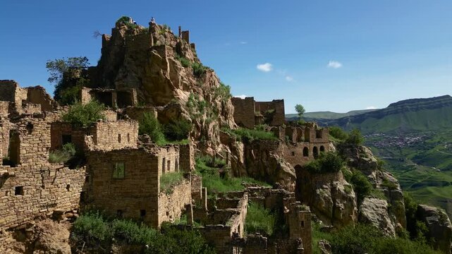 Drone aerial view of the abandoned mountain village of Gamsutl in Dagestan at sunrise with soft golden morning light and dramatic scenery.